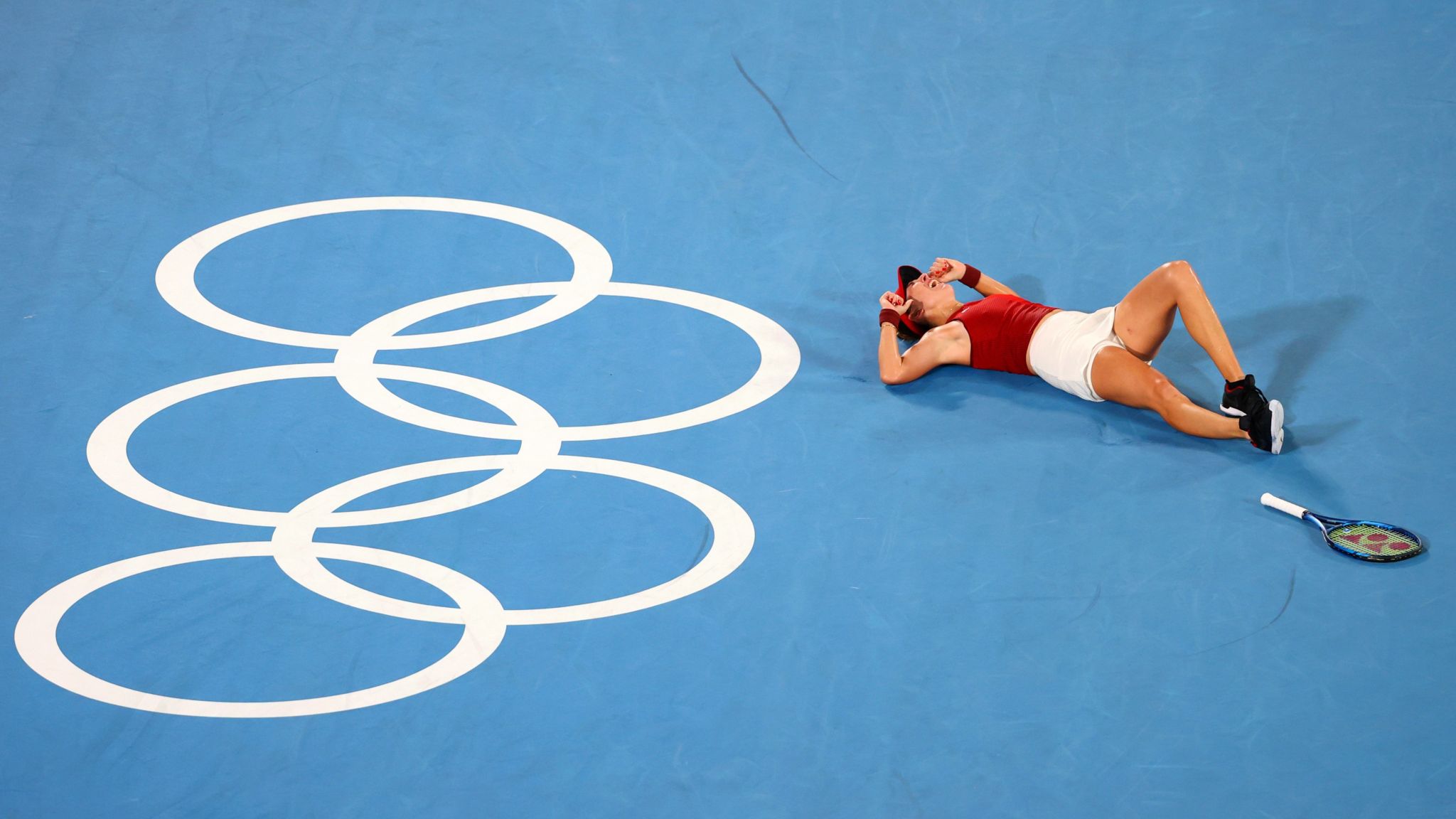 Olympic tennis player serves under a bright sky